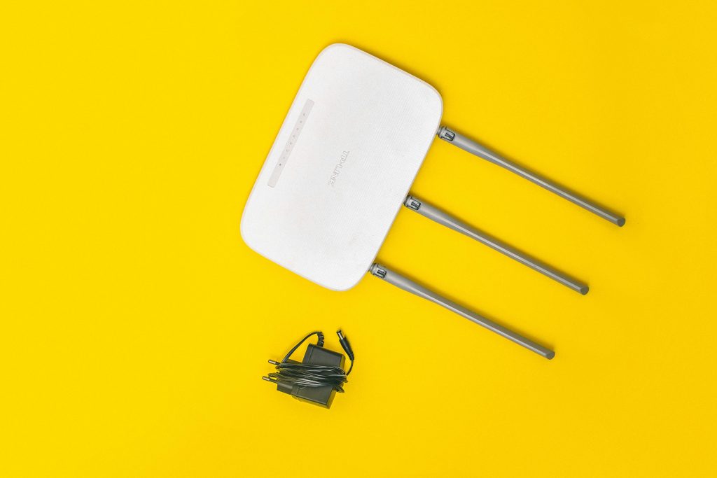 White router with three antennas and cables on bold yellow background, ideal for tech concepts.